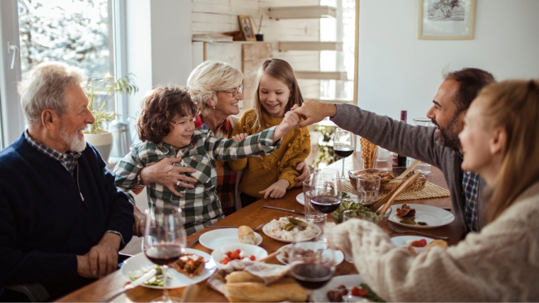 A family sitting and laughing around a table at the holidays | Holiday Traditions and Mental Health Discover the Positive Impact | Mindful Health Solutions