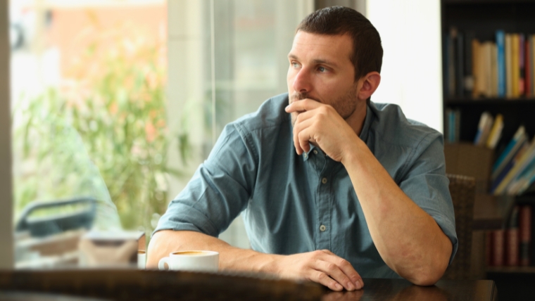 Man sitting in coffee shop looking out the window | TMS vs. Traditional Antidepressants Which Works Best for You | Mindful Health Solutions