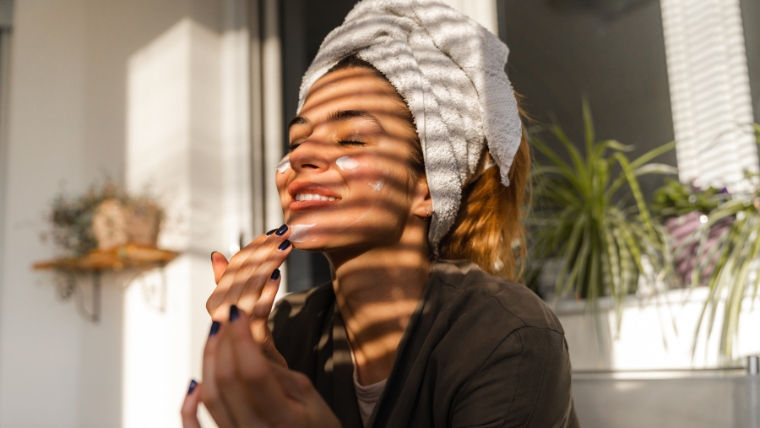 How-To-Build-Healthy-Habits-and-Embracing-Self-Care-in-the-New-Year Woman with a towel around her hair applying face cream | How To Build Healthy Habits and Embrace Self-Care in the New Year | Mindful Health Solutions