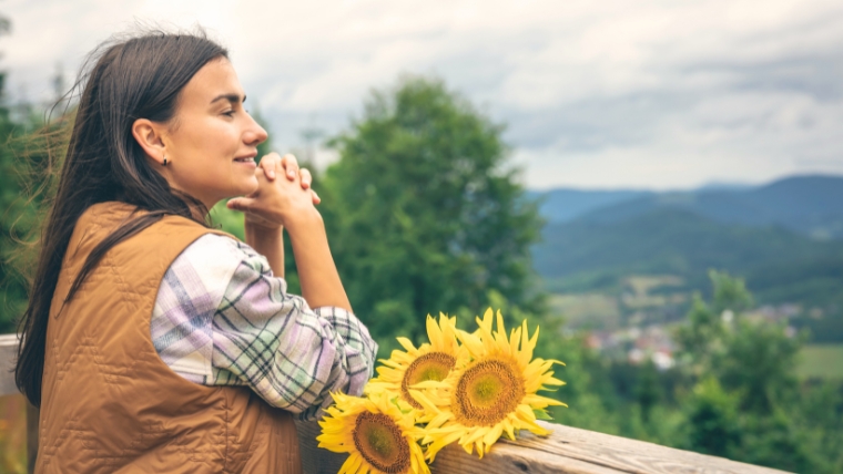 Self-Love-How-To-Grow-a-Strong-and-Loving-Relationship-with-Yourself Young woman looking at sunflowers on a wooden deck | Self-Love: How To Grow a Strong and Loving Relationship with Yourself | Mindful Health Solutions